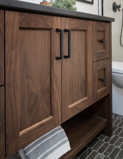 A bathroom with wooden cabinets and a black tile floor.