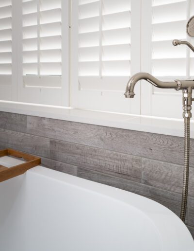 A bathtub with a wooden tray and wooden shutters.