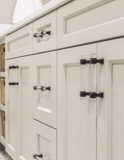 A laundry room with white cabinets and black handles.