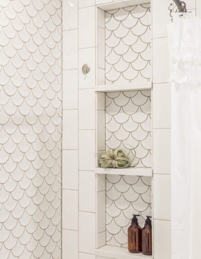 A white tiled shower with a fish scale pattern.