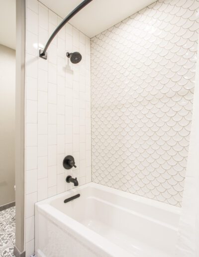 A white and black bathroom with a tub and shower.