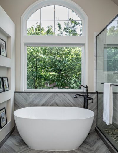 A white bathtub in a bathroom with a window.