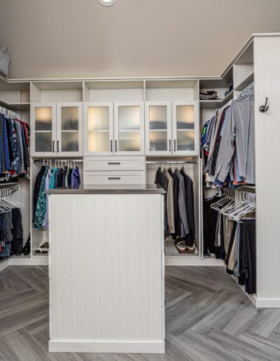 A walk in closet with a lot of clothes in it.