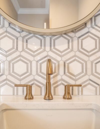 A bathroom with a white sink and gold faucet.