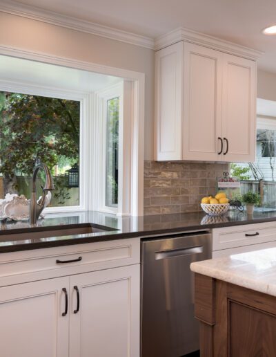 A kitchen with white cabinets and a large window.