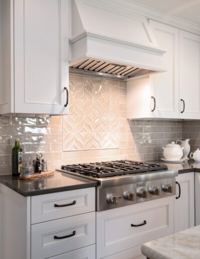 A white kitchen with marble counter tops and a stove.