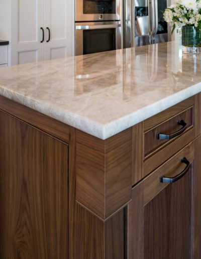 A kitchen with a marble counter top and wooden cabinets.